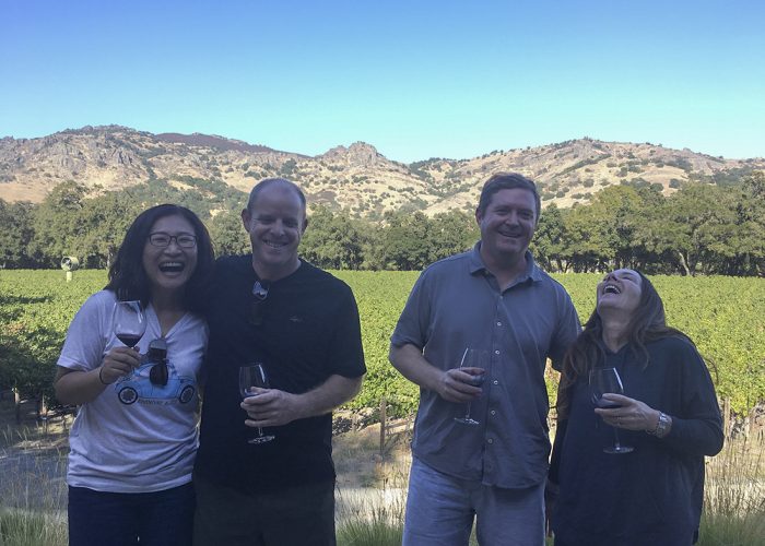 two couples laughing and enjoying wine tasting