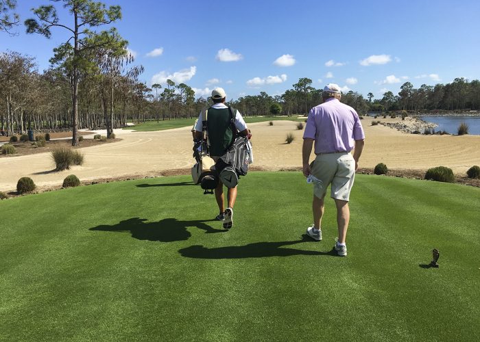 golfer and caddie walking on a golf course
