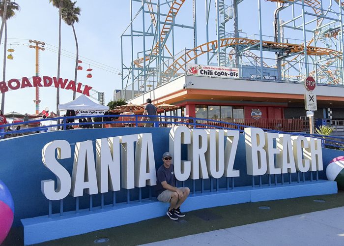 man in front of Santa Cruz Beach sign
